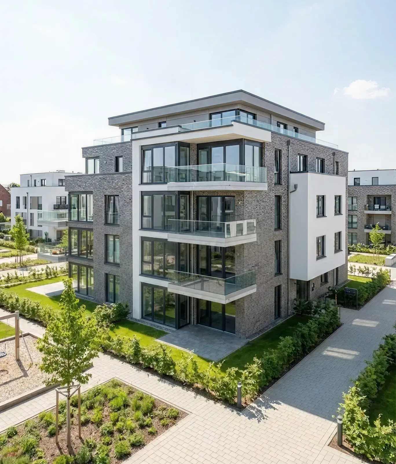 Außenansicht eines modernen Mehrfamilienhauses mit grauer Klinkerfassade und großzügigen Glasbalkonen, ideal für die Vermietung oder den Verkauf durch Straub Immobilien.